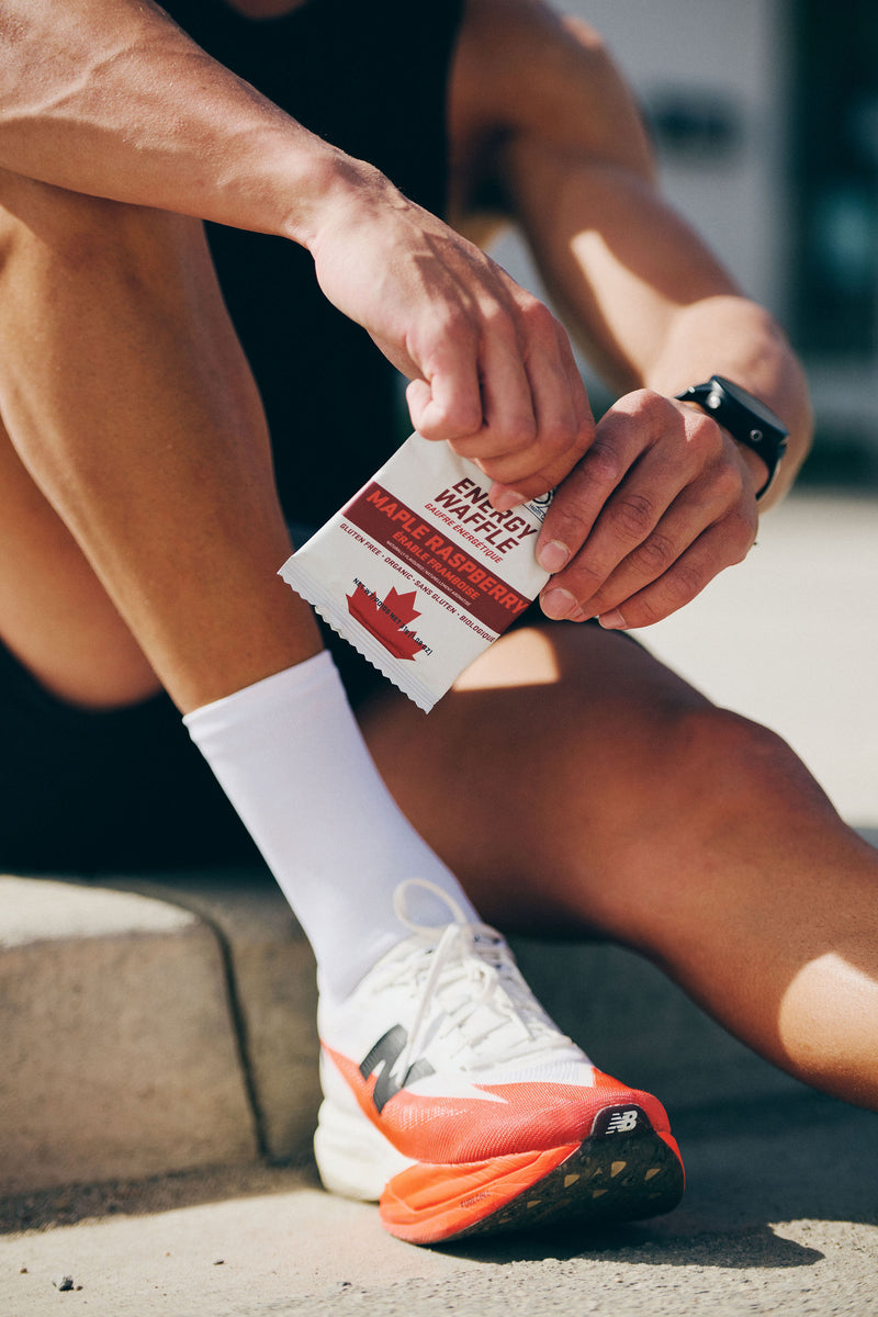 Runner opening a Grynd Maple Raspberry Gluten Free Energy Waffle before a run — clean organic race day fuel for Canadian runners